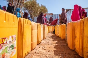 Displaced women line up to fill their jerrycans