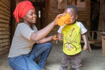A farmer drinks water from a nearby prosper global water tap with their 5 year-old son.