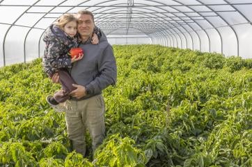 In ukraine, serhii and his daughter stand inside a new greenhouse.