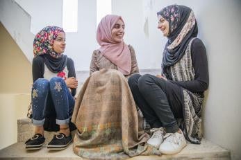 A prosper global volunteer girls’ science teacher, talks with her students while they sit on stairs. 