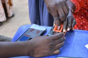 A prosper global team member assists an e-voucher recipient with a digital identity process, increasing security and efficiency.