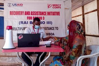 A prosper global team member registering a community member for monthly e-vouchers so she can purchase food for her family.