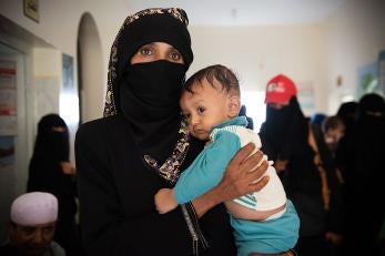 A woman holding her infant son in yemen