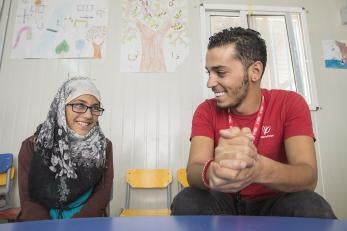 A prosper global team member sits next to a girl, both smiling and talking, in jordan