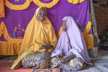 A mother her daughter sit in their home built by prosper global.