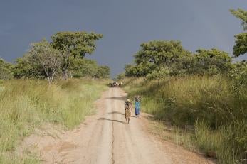 Landscape in rural Uganda with two villagers walking down a dirt road