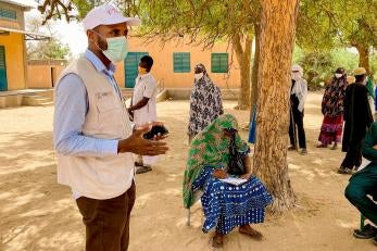 Participants in Tillaberi Region, Niger, listen to a Prosper Global representative wearing a facemask explaining details about a program.