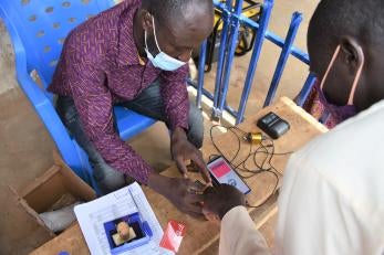 A Prosper Global team member assists an e-voucher recipient with a digital identity process, increasing security and efficiency.