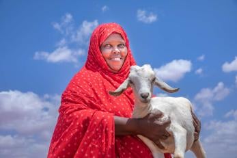 A pastoralist and livestock owner holding one of their goats.