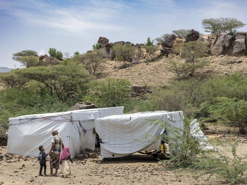 Family stands in front of makeshift shelters in Yemen.