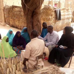 A group of community members gathered outdoors, seated