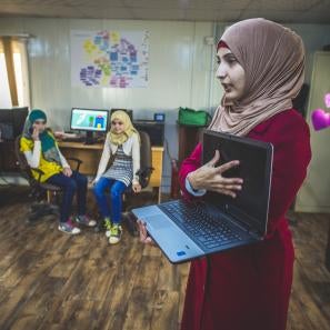 A woman showing a laptop computer to a group