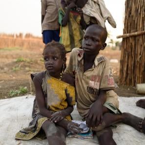 Brother and sister sit on a blanket