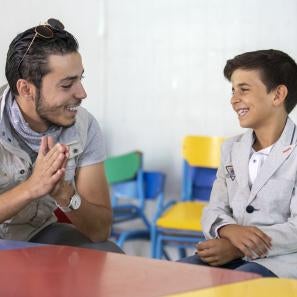 At a youth center in zaatari, omar al-tal sits with mohammad. mohammad is able to play sports and games while learning important life skills like computers and english. two of mohammad’s favorite activities are playing foosball and soccer, but his favorite is singing. at a recent talent show in the center, he finished third. photo: ezra millstein/mercy corps