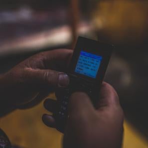 A pair of hands uses a mobile phone to send an sms text. 