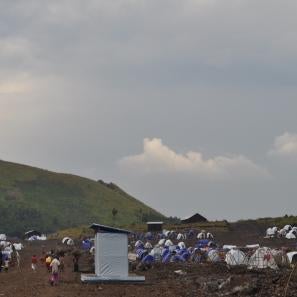 Families move about a camp with temporary living structures.