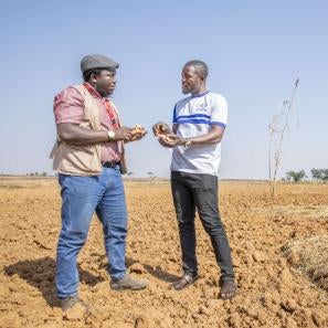 Two people having a conversation in a field.