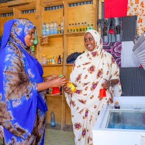 Two kenyan women interact in a commercial environment.