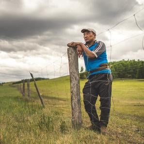 Mongolian farmer looking over a landscape view of agricultural land.