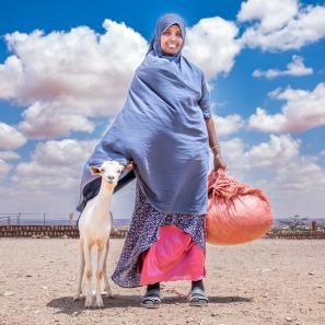 Ethiopian woman with her goat stand on the plains.