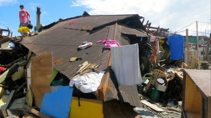 Alan Habinada stands on the roof of a collapsed house during his first visit to his hometown since the typhoon struck. He returned to bring relief goods to his mother and look for his missing fiancée. Sadly, he learned a few hours later that she had been killed.