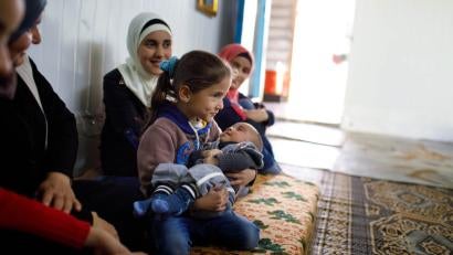 Baby supplies are tremendously helpful for growing refugee families like Eman’s (blue headscarf). She lives in a caravan in Zaatari with her newborn, Inas, and her other children. Photo: Annie Sakkab/Prosper Global