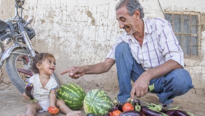 Abu Goubran with his granddaughter Wia, 1, and a pile of freshly harvested eggplant, tomatoes and watermelon. Farming expertise like his will be critical to Syria's communities as they look to the future. Local farmers come here for training sessions on innovative farming techniques. “I’m so happy to share what I know,” he says.