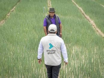 Prosper Global employee meets with community member in agricultural setting.